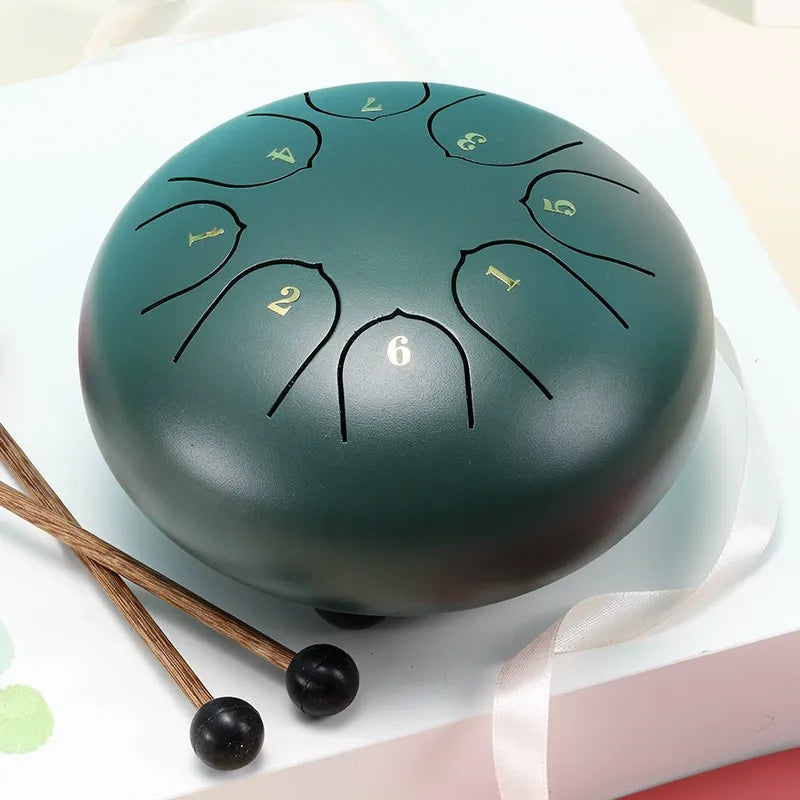 A calming, sage green 6-inch 8-note steel tongue drum, a therapeutic handpan for sound baths.