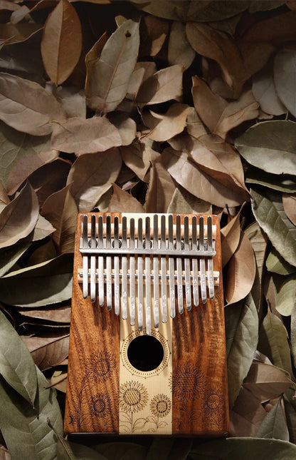 Close-up of the metal tines on a 17-key kalimba with engraved musical notes, ideal for beginners using tuning apps to ensure the frequency is set for a perfect meditative and healing sound.