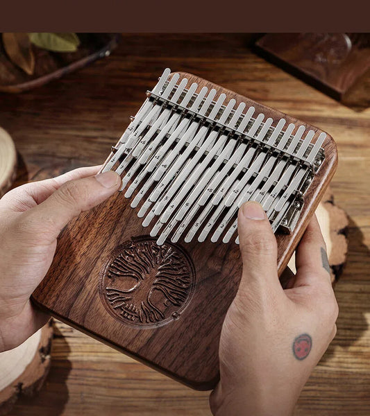 Close-up of a hand holding a dark wood kalimba with polished metal tines, showcasing the natural grain and artistic craftsmanship.