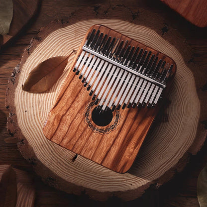 MoralGain® Master 21-key solid wood flat board kalimba with a round-edge design, placed on a bed of autumn leaves to showcase its professional aesthetic and natural wood grain.