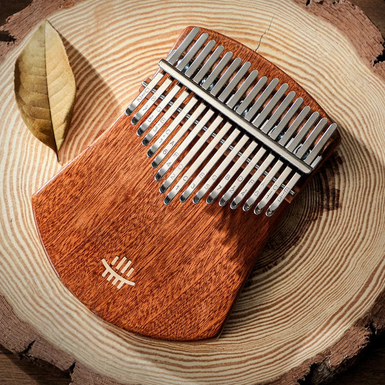 A 17-key solid wood kalimba by Moral Gain, resting on a circular wood slab base, featuring deep brown wood grain and polished metal tines with engraved note markings.