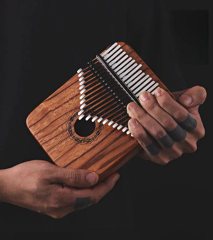 Close-up of a 21-key hollow-body kalimba with professional manganese steel tines and a hand-polished Gaboon Rosewood resonant box, ideal for intermediate players and sound therapy.